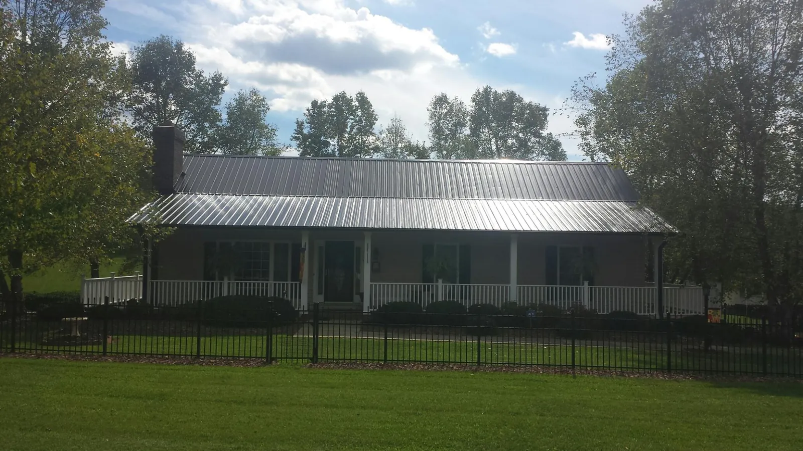 Gray metal roof on a brick ranch with a full width front porch — Gutter Guard Installation work by our crew in Birmingham